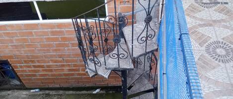 Un escalier avec des rampes en métal, un mur en briques et un sol à motifs.