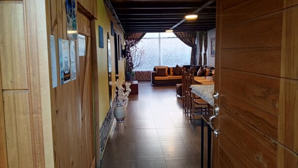 A wooden interior with a dining area, a sofa, and a view through a window.