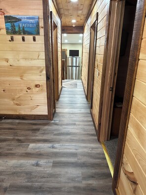 A wooden interior hallway with a view of a lake and mountains, a stainless steel refrigerator, and a patterned rug on the floor. - Cozy 2-bedroom house in Nancy, 2 Miles From Wolf Creek Marina! Plenty of parking (Nancy)