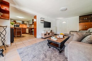 A modern living room with a sofa, a coffee table, and a kitchen in the background. - Family Retreat near Zagreb with Pool & Garden, Velika Buna, Croatia (Velika Buna)