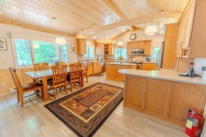 A spacious kitchen with wooden cabinets, a dining area with a table and chairs, and large windows.