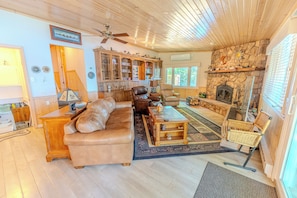 A spacious living room with a fireplace, leather sofas, a wooden coffee table, and a stone fireplace surround.