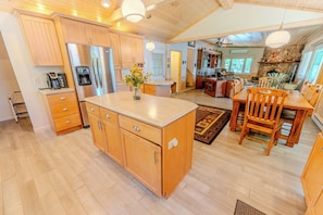 A spacious kitchen with wooden cabinets, a central island, and a dining area with wooden chairs and a table.