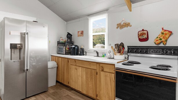 Eine moderne Küche mit einem Edelstahl-Kühlschrank, einem eingebauten Ofen und Holzschränken.