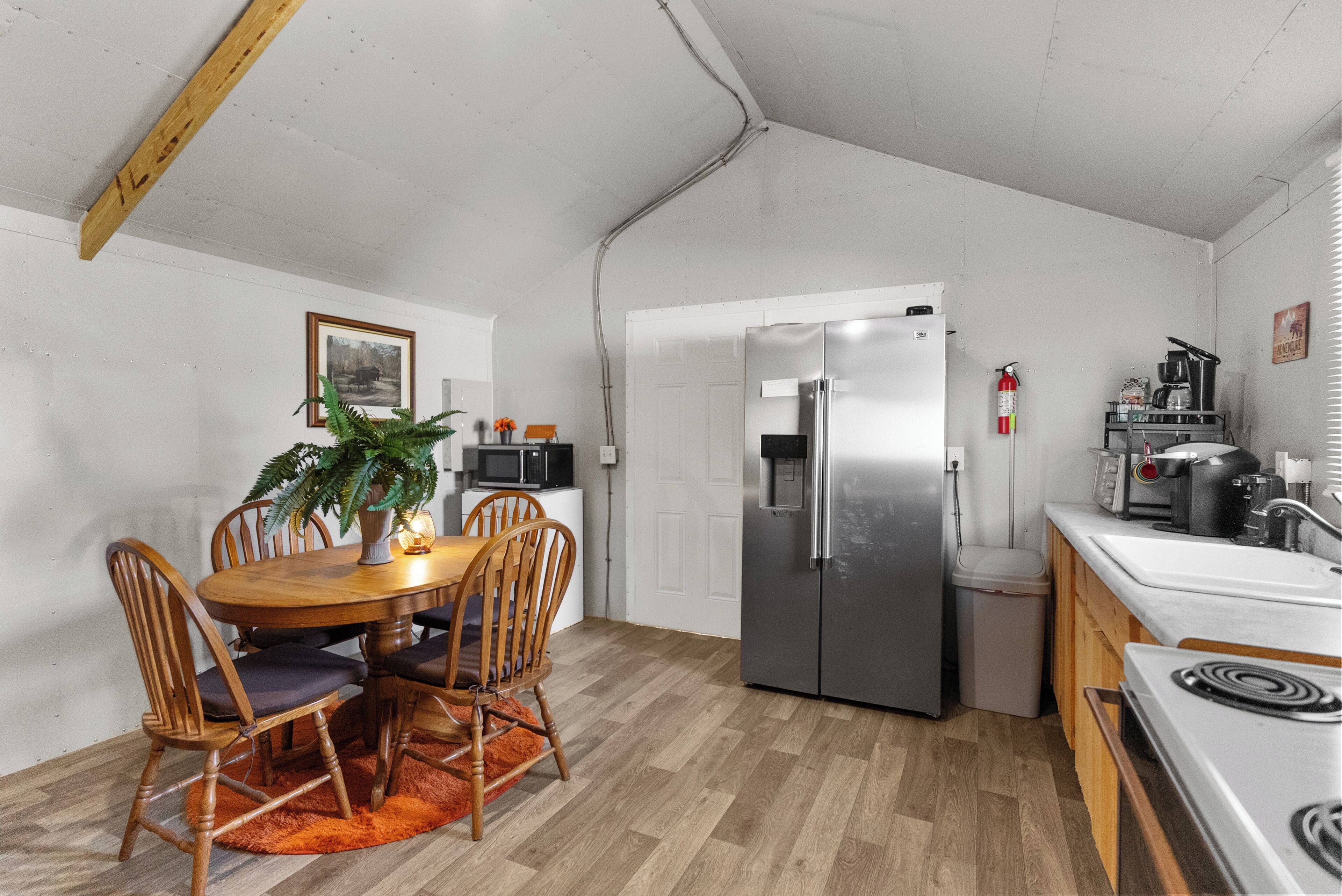 A compact kitchen with a dining area, a refrigerator, a microwave, and a stove.