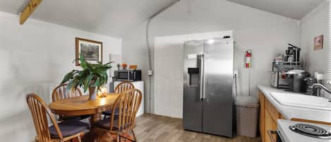 A compact kitchen with a dining area, a refrigerator, a microwave, and a stove.