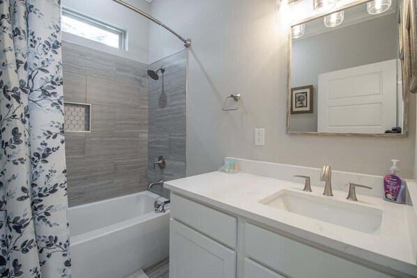 A bathroom with a shower, a bathtub, a sink, and a mirror. - The Southern Sea Haven (Gulfport)