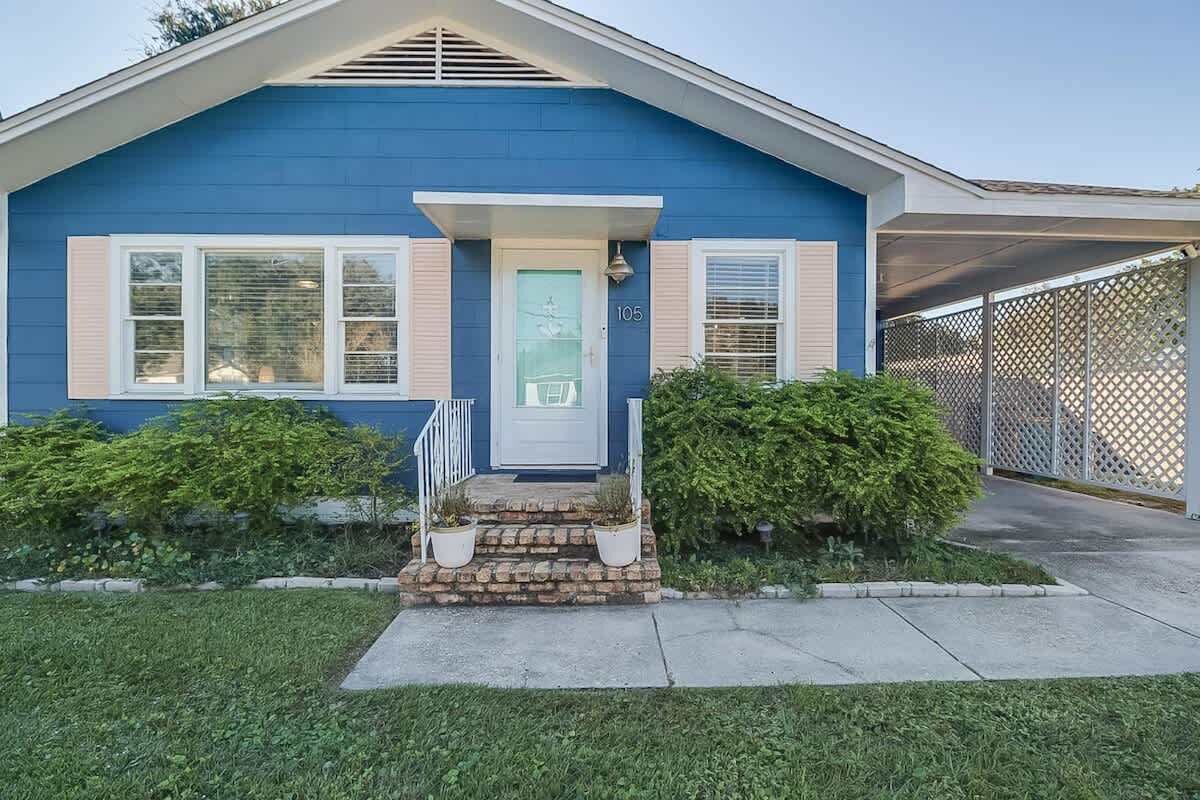 A single-story house with a blue exterior, a front door, and a small porch with steps.