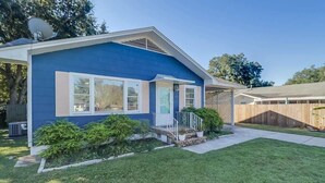 A single-story house with a blue exterior, a front porch, and a small front yard. - The Cozy Blue Cottage (Long Beach)