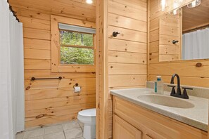 Ein Badezimmer einer Holzhütte mit Toilette, Waschbecken und Fenster.