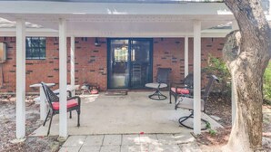 Ein überdachter Patio-Bereich mit Gartenmöbeln und einem Backsteinhaus im Hintergrund.