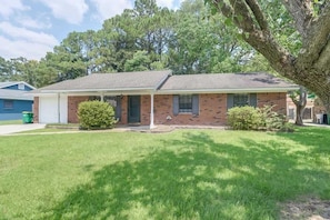 A two-story house with a brick exterior, a covered front porch, and a well-maintained lawn. - Whimsical Escape in Ocean Springs (Ocean Springs)