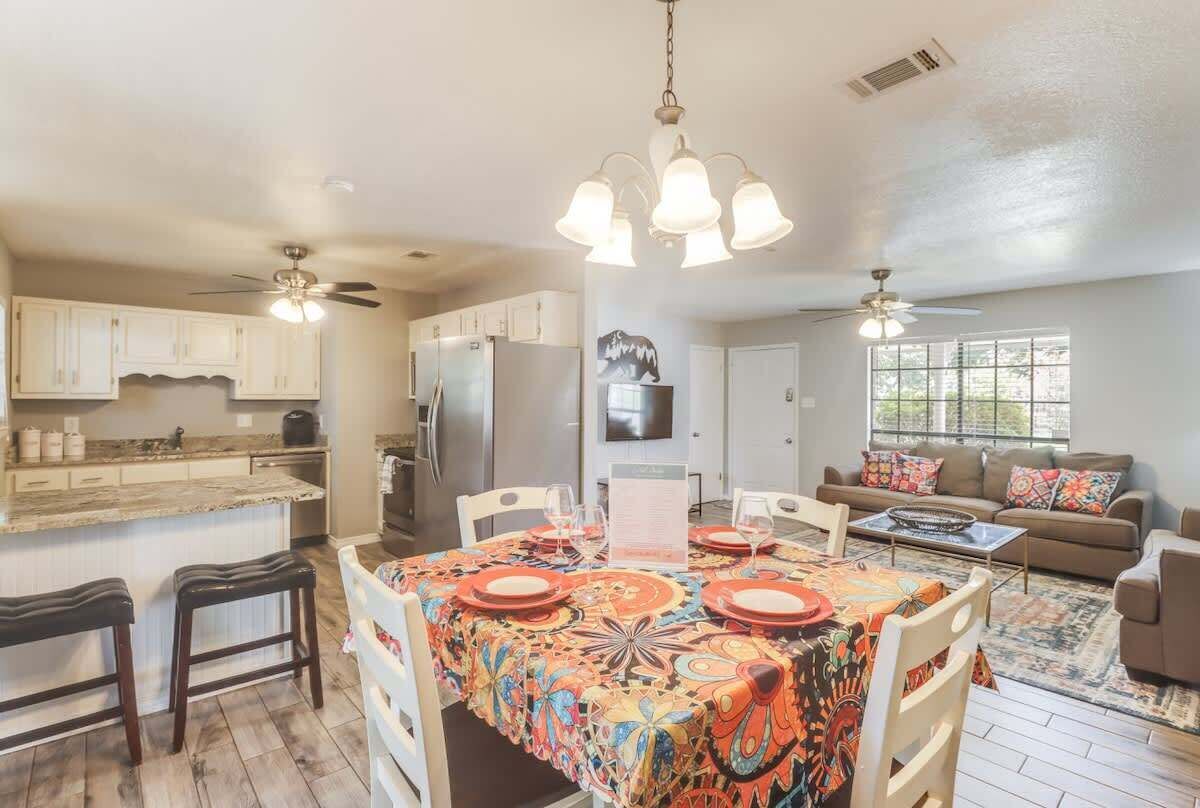 A modern kitchen with a dining area, a living room, and a large window.