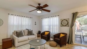 A living room with a ceiling fan, two sofas, a coffee table, and a view through a glass door. - The Gulf Breeze Getaway (Gulfport)