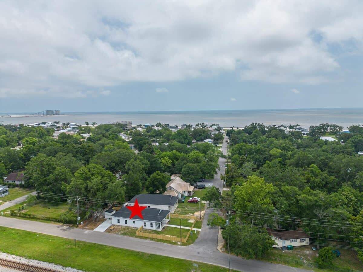 A residential area with houses, a road, and a body of water in the background.