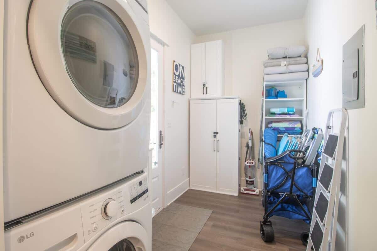 A laundry room with an LG washing machine, a cabinet, a cart with cleaning supplies, and a sign that says 'ON BEACH TIME'.