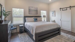 Une chambre à coucher avec un lit, des tables de chevet, un ventilateur de plafond et une porte.