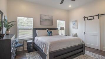 A bedroom with a bed, bedside tables, a ceiling fan, and a door.
