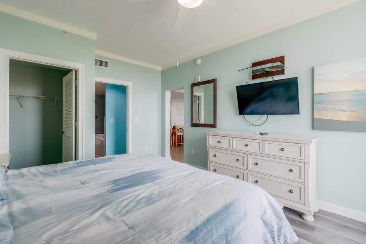 A bedroom with a bed, a dresser, a television, and a painting on the wall.