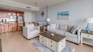 Una sala de estar moderna con sofá, mesa de centro y área de cocina con taburetes de bar.