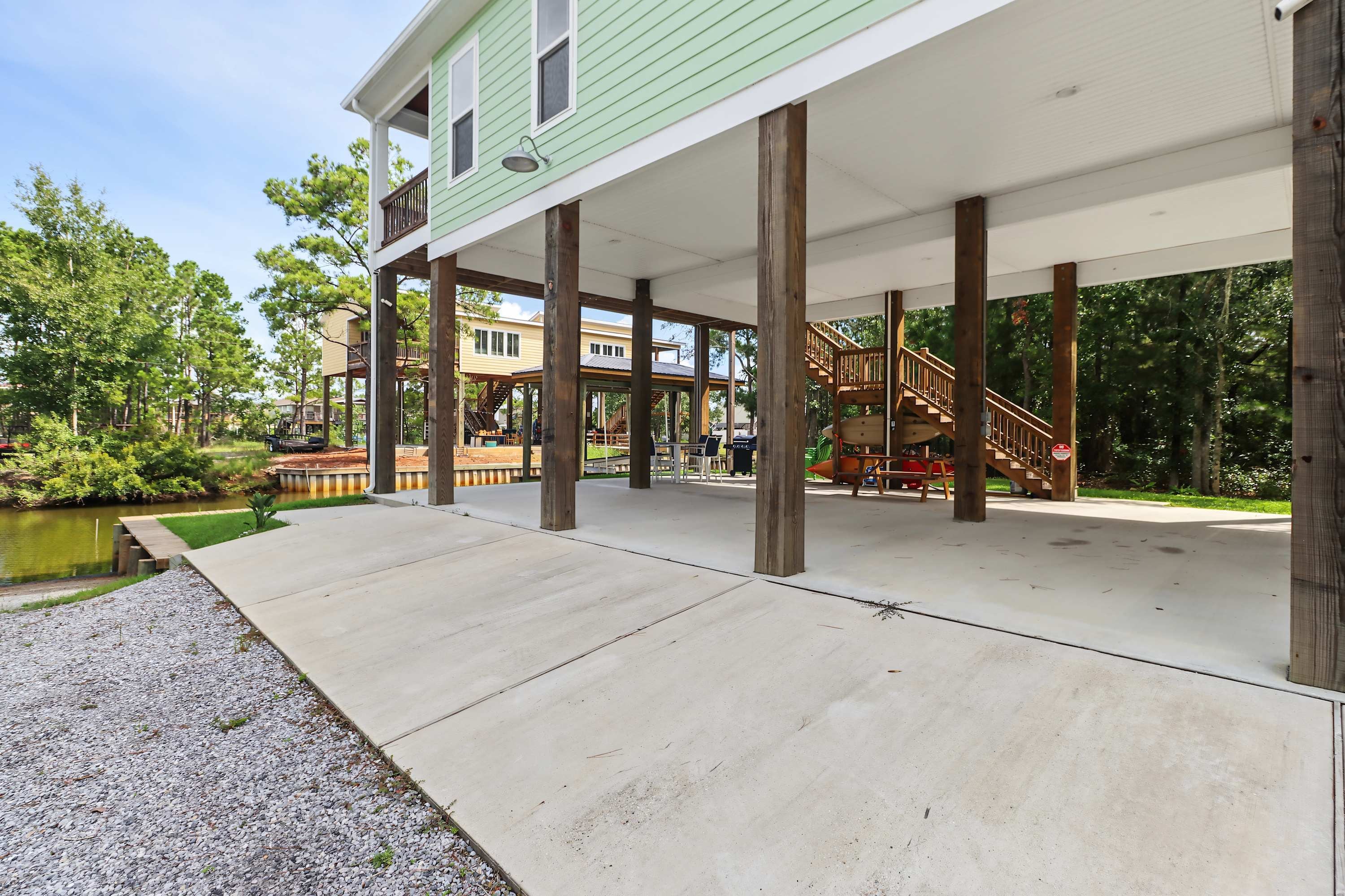 A covered outdoor area with a concrete floor, wooden pillars, and a view of a lake.