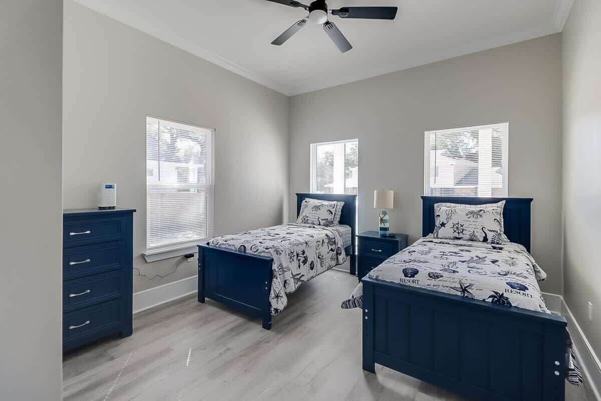 A bedroom with two beds, a ceiling fan, and a dresser.