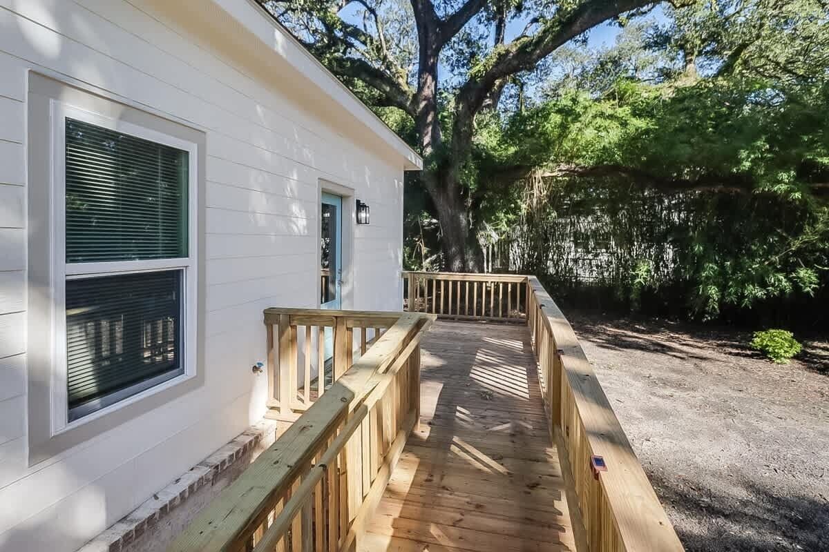 A white building with a wooden deck leading to a covered porch.