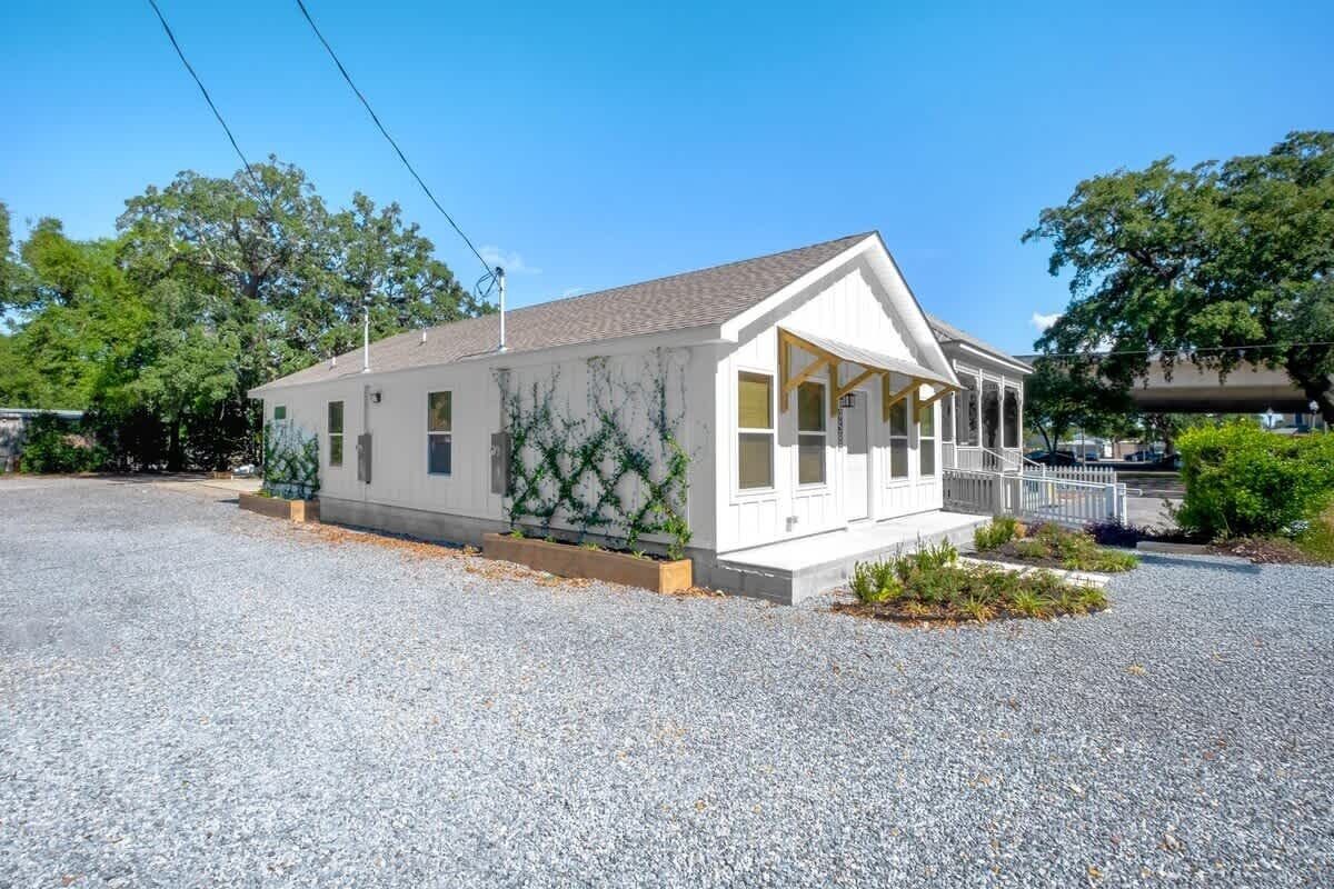 A single-story building with a gabled roof, a covered porch, and a gravel driveway.