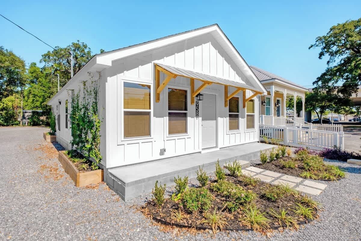 A white single-story house with a porch, a garage, and a small garden area.