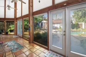 A covered patio area with sliding glass doors, a ceiling fan, and a view of a backyard with a pool. - Shadow Beach Retreat (Pass Christian)