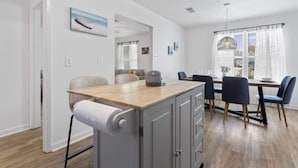 Una cocina moderna con encimera de madera, horno empotrado y zona de comedor con mesa y sillas.