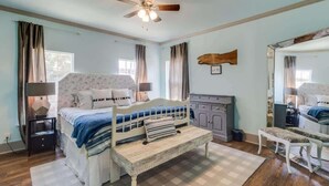 A bedroom with a bed, a bench, a dresser, a mirror, and a ceiling fan. - Miazza Cottage in Gulfport (Gulfport)