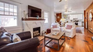 A living room with a fireplace, white sofas, a coffee table, and a ceiling fan. - Miazza Cottage in Gulfport (Gulfport)