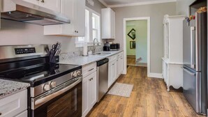 A modern kitchen with white cabinets, stainless steel appliances, and a wooden floor. - Miazza Cottage in Gulfport (Gulfport)