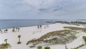 A beach with sand, palm trees, and a pier extending into the water. - Endless Blue at the Gulf Watch (Biloxi)