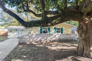 A house with a large tree in front, a driveway, and a small front yard. - The Magnolia Retreat (Gulfport)