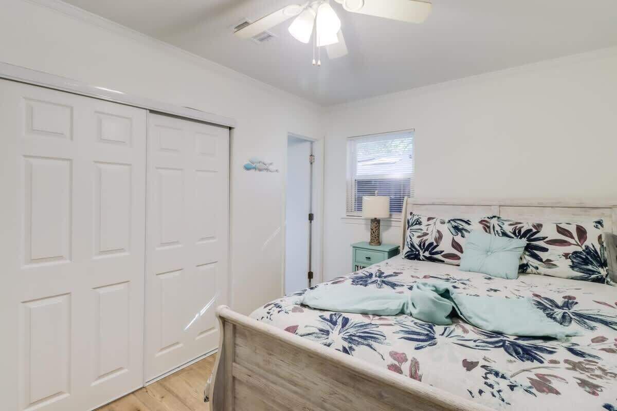 A bedroom with a bed, a nightstand, a window with blinds, and a ceiling fan.