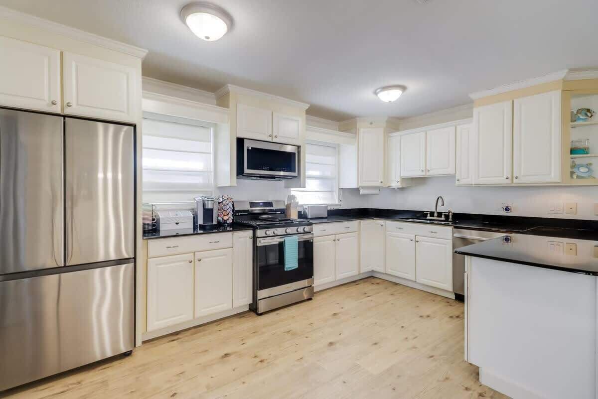 A modern kitchen with white cabinets, stainless steel appliances, and a black countertop.