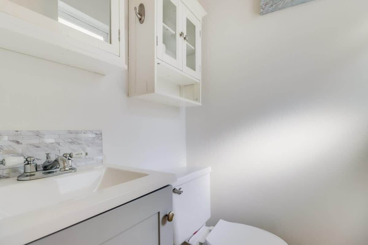 Une salle de bain avec un lavabo blanc, des toilettes et un meuble au-dessus du lavabo.