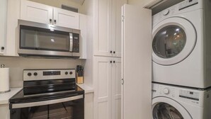 Uma cozinha compacta equipada com micro-ondas, forno e máquina de lavar e secar empilhadas.