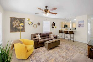 Una sala de estar con sofá, sillón, mesa de centro y ventilador de techo.