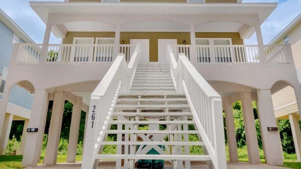A two-story house with a central staircase, a balcony on each floor, and a number '261' on the staircase. - Cozy 2 Bed Duplex Just Blocks From Downtown Biloxi! (Biloxi)