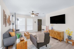 Una sala moderna con sofá, mesa de centro, televisor y ventilador de techo.