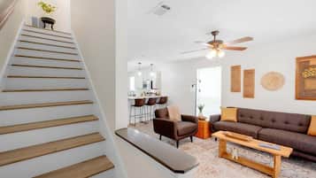 A staircase leading to a living area with a sofa, a coffee table, and a ceiling fan.