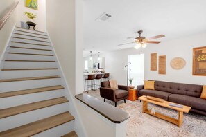A staircase leading to a living area with a sofa, a coffee table, and a ceiling fan. - Cozy 2 Bed/1.5 Bath Duplex Just Blocks From Downtown Biloxi! (Biloxi)