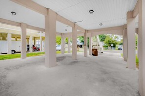 Uma área de estacionamento coberta vazia, com piso de concreto e pilares brancos.