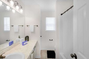 A bathroom with a sink, mirror, towel rack, shower, and a window. - Cozy 2 Bed/1.5 Bath Duplex Just Blocks From Downtown Biloxi! (Biloxi)