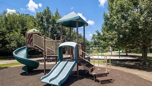 A playground with a slide, climbing structures, and a covered seating area. - Cottage on Broadmoor (Gulfport)