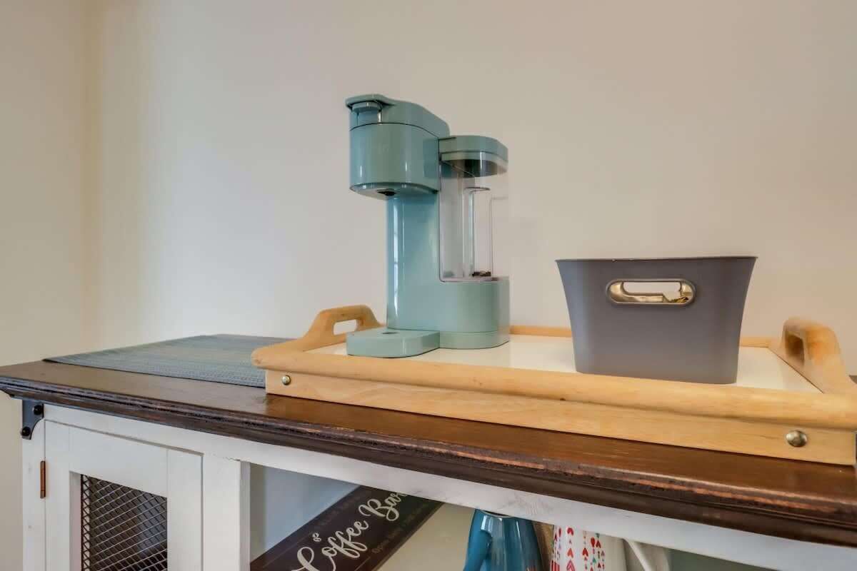 A coffee machine, a kettle, and a container on a wooden tray.