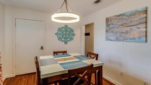 Un comedor con una mesa, sillas, una lámpara colgante, un adorno de pared y un cuadro.